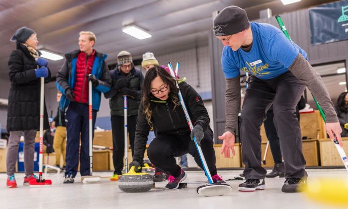 An instructor helping a first-time curler on the ice